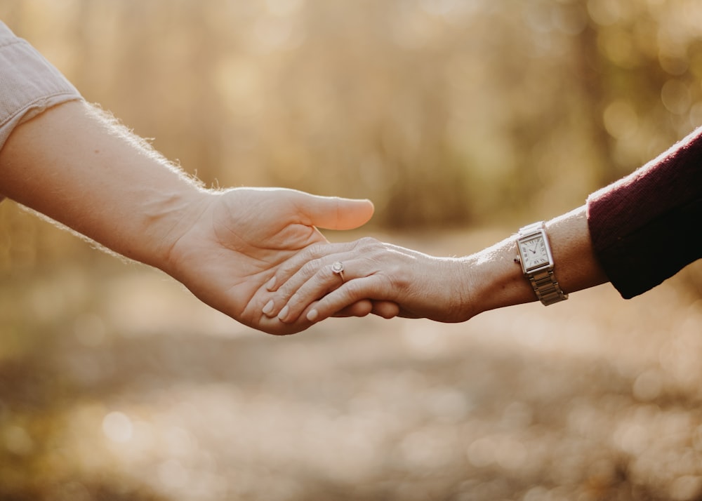 a close up of two people holding hands