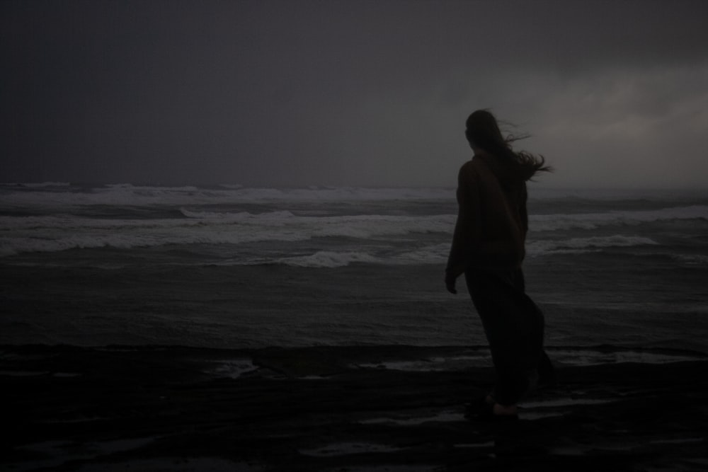Eine Person, die im Dunkeln am Strand steht