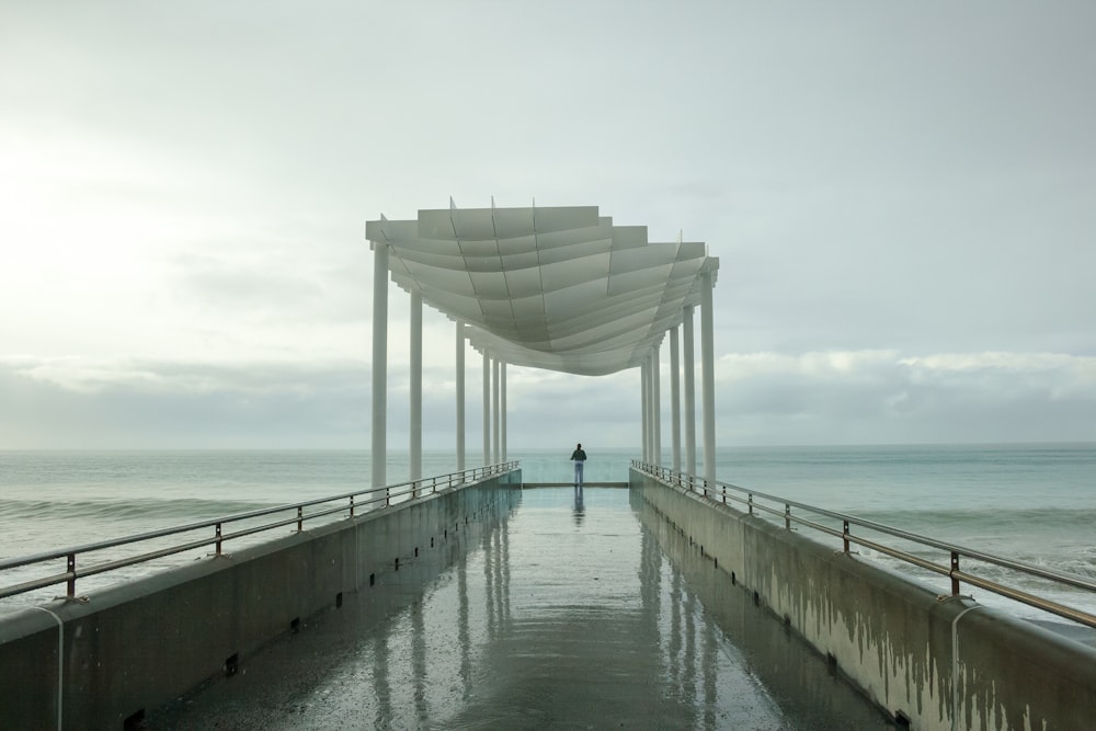 uma pessoa em pé em um píer ao lado do oceano