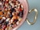 A copper pot filled with a colorful mixture of chopped fruits, including apples, grapes, and berries, creating a vibrant fruit medley. The pot has a detailed brass handle, adding a touch of elegance.