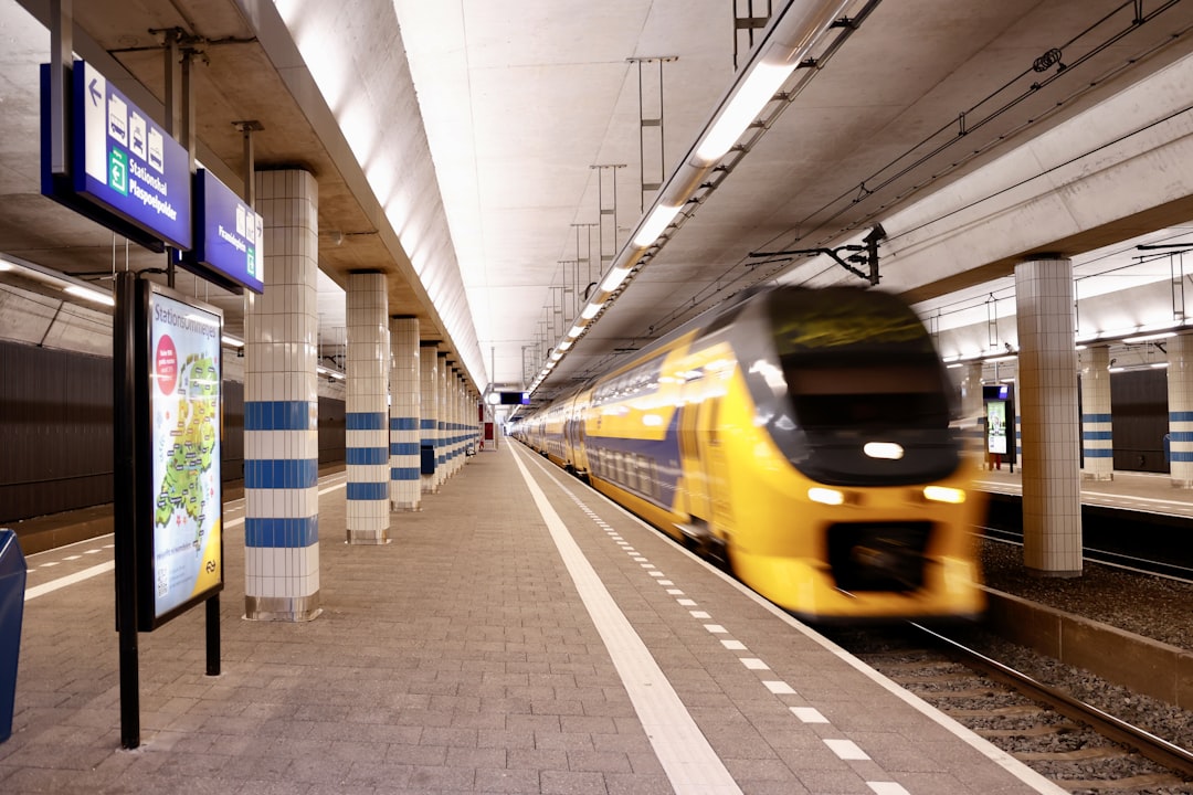 a yellow train is coming down the tracks, Dutch NS train passing through Rijswijk station. Nederlandse Spoorwegen.