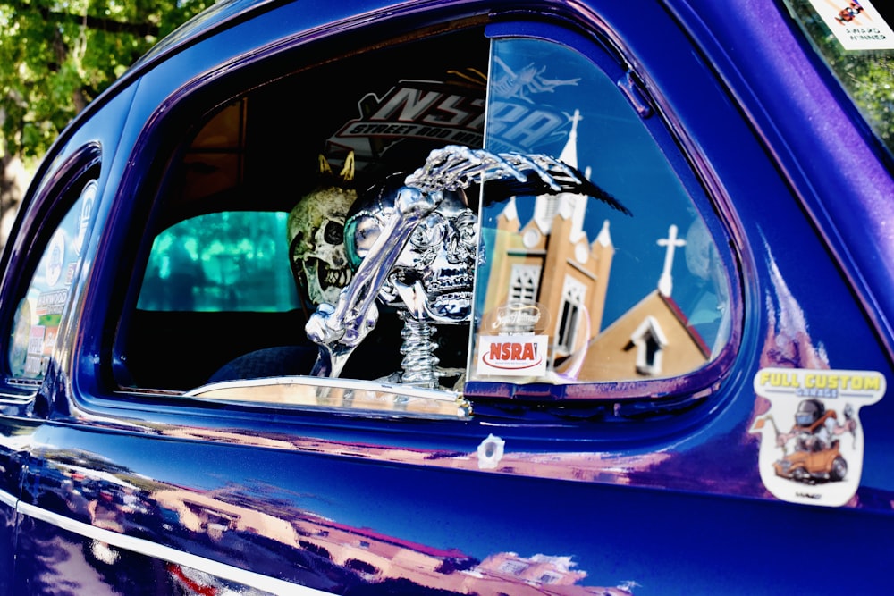 a blue car with a skeleton in the rear window