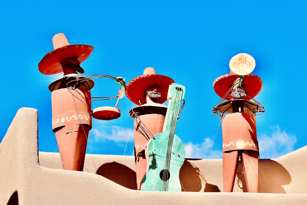 three sculptures of people with hats on top of a building