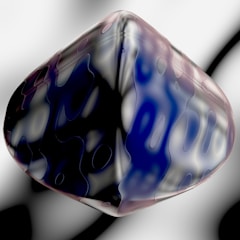 A three-dimensional, abstract object resembling a distorted, smooth cube with a glossy surface. It features a blend of dark blue, black, and white swirled patterns throughout its structure. The background is a soft gradient of grayscale, contributing to a subtle and futuristic feel.