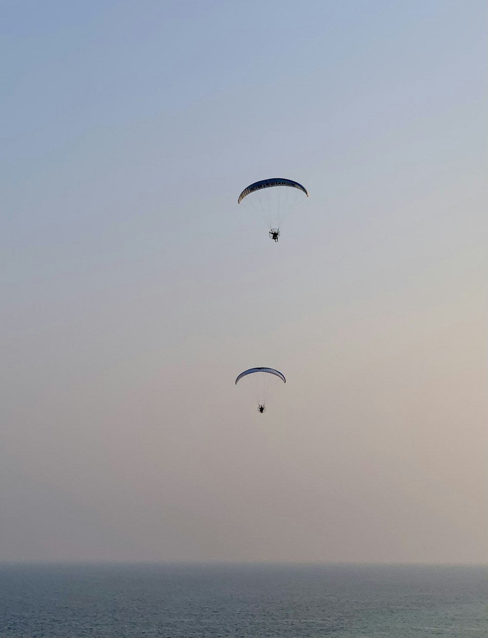 a couple of parasailers are flying over the ocean