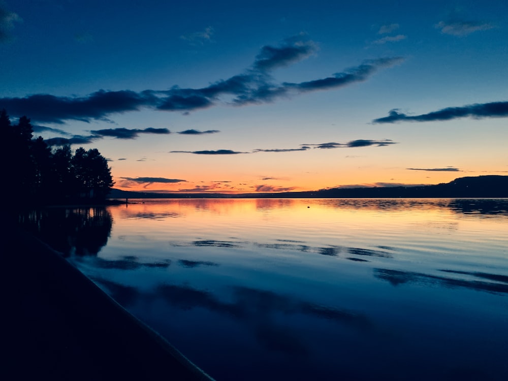 a body of water with a sunset in the background