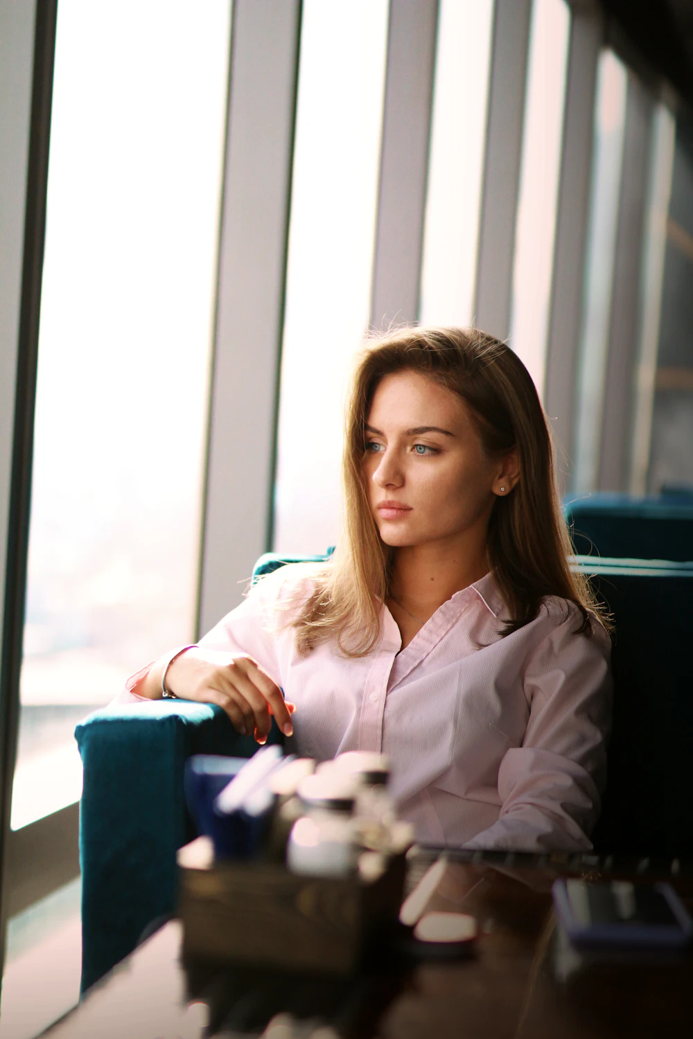 A professional sitting by a sunlit office window with a coffee cup