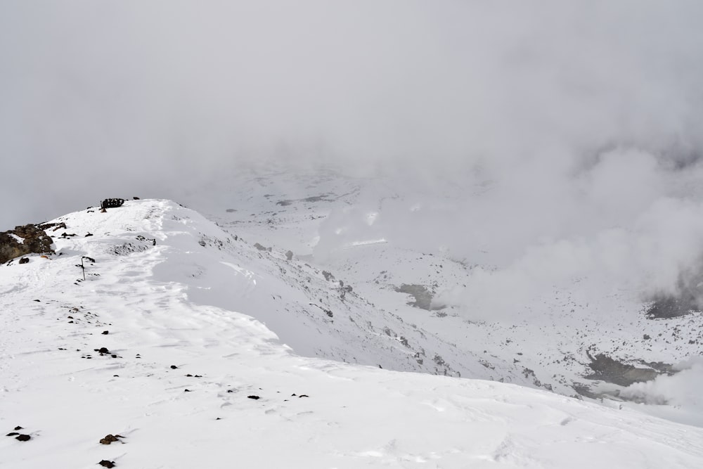 a mountain covered in snow and clouds on a cloudy day