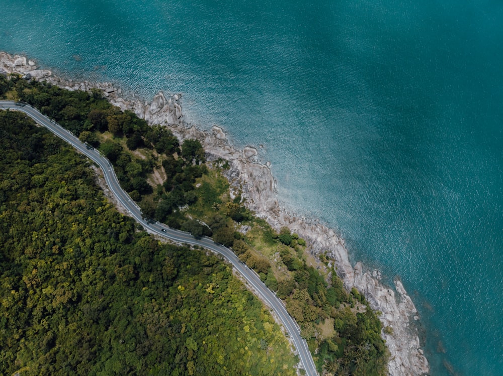 an aerial view of a winding road next to a body of water