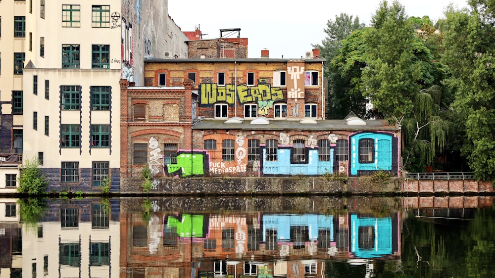a building with graffiti on the side of it next to a body of water
