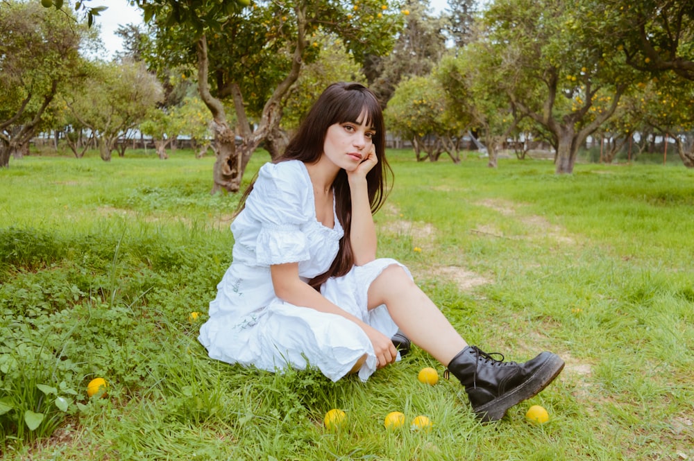 a woman in a white dress is sitting in the grass