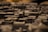 A close-up view of a detailed miniature model of a city with various buildings and structures, mostly composed of dark tones. The depth of field creates a blurred background effect, emphasizing the textured surfaces of the miniature buildings.