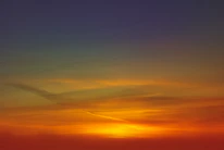 A vibrant sunset captured from above, showing rich colors and detailed landscape textures.
