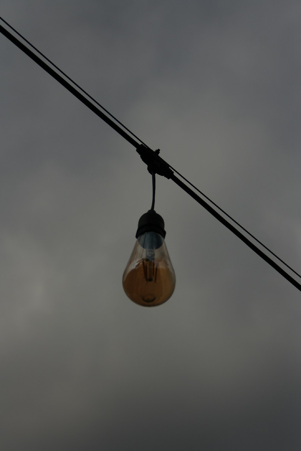 a light bulb hanging from a wire on a cloudy day