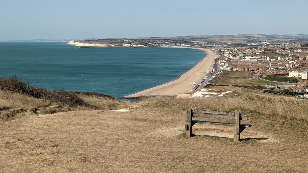 a wooden bench sitting on top of a grass covered hillside