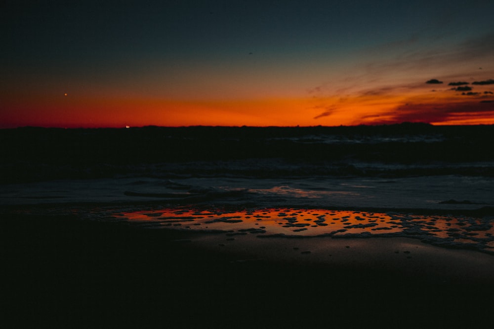 the sun is setting over the ocean on the beach