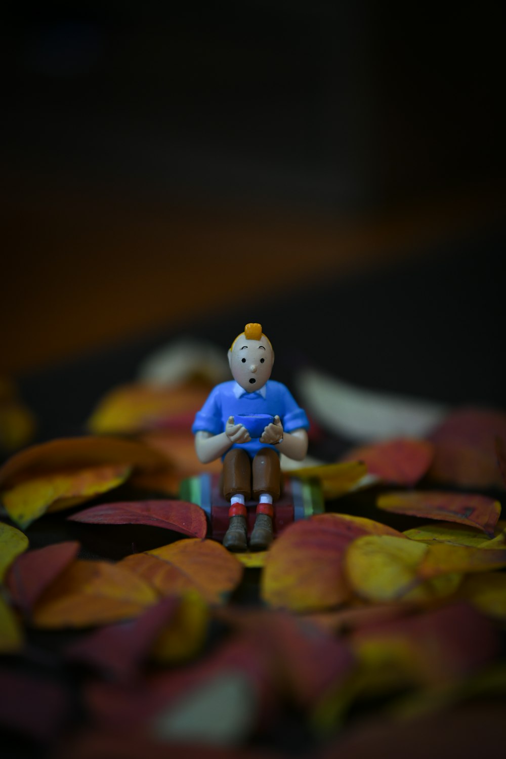 a small figurine sitting on top of a pile of leaves