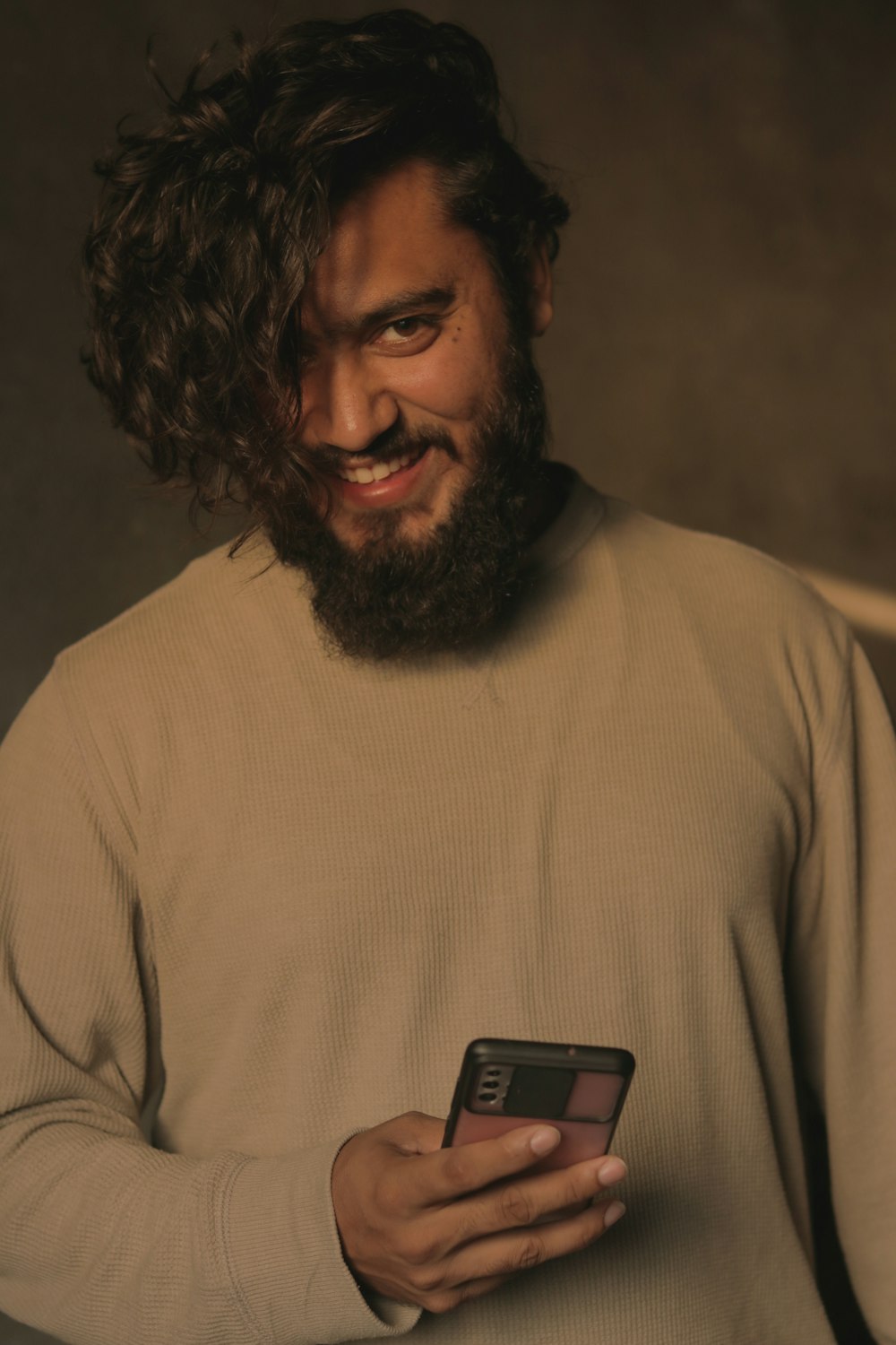 Un homme avec une barbe tenant un téléphone portable