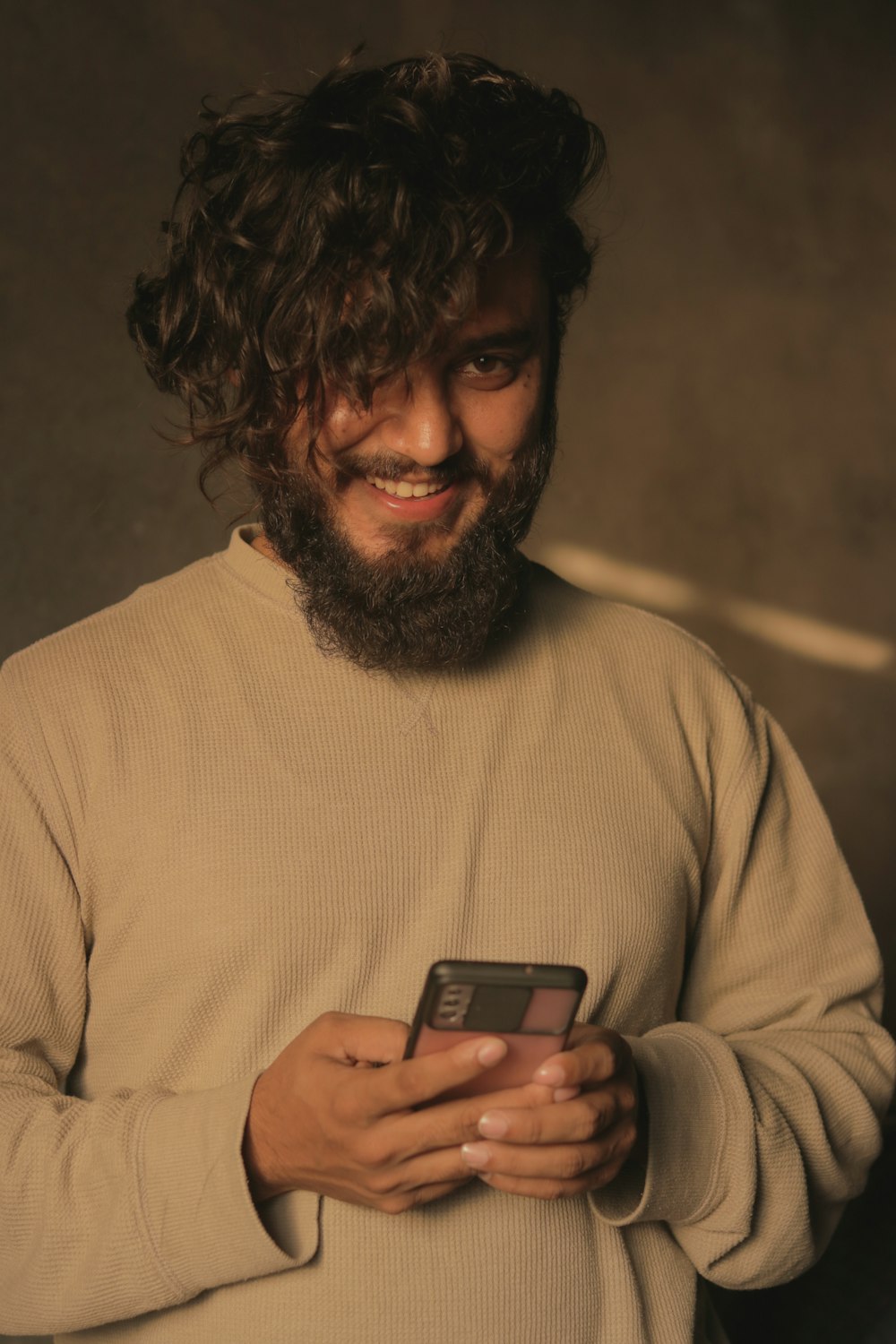 a man with a beard holding a cell phone
