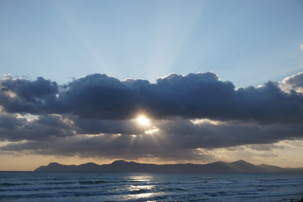 the sun is shining through the clouds over the ocean