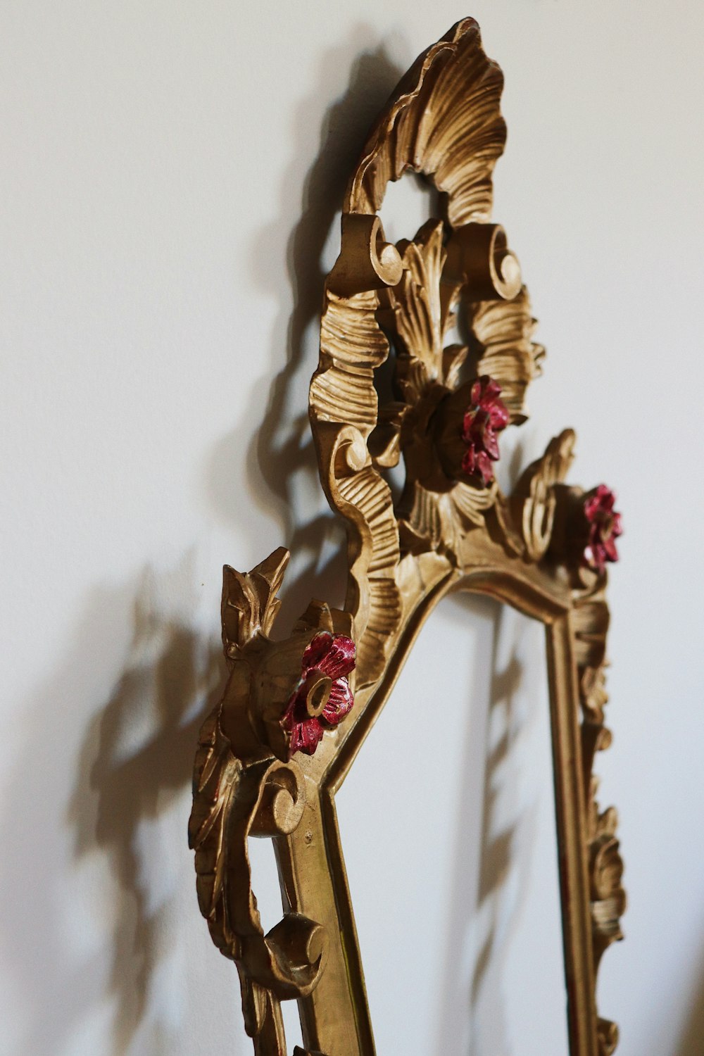 a gold ornate mirror with red flowers on it