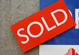 a red sold sign sitting on top of a blue sign