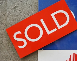 a red sold sign sitting on top of a blue sign