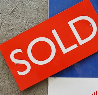 a red sold sign sitting on top of a blue sign