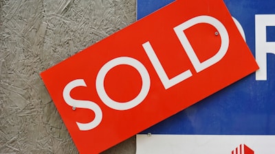 a red sold sign sitting on top of a blue sign