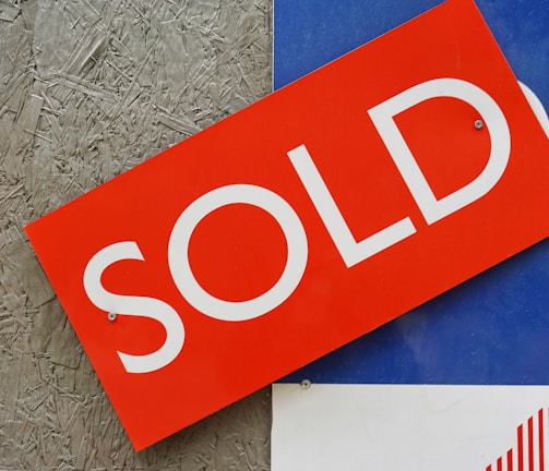 a red sold sign sitting on top of a blue sign