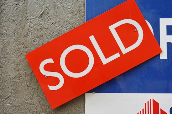 a red sold sign sitting on top of a blue sign