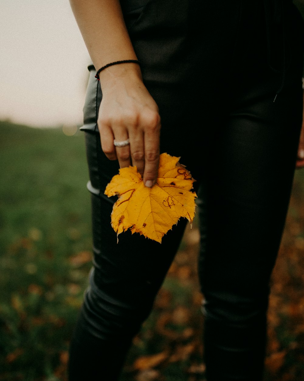 a woman holding a yellow leaf in her hand