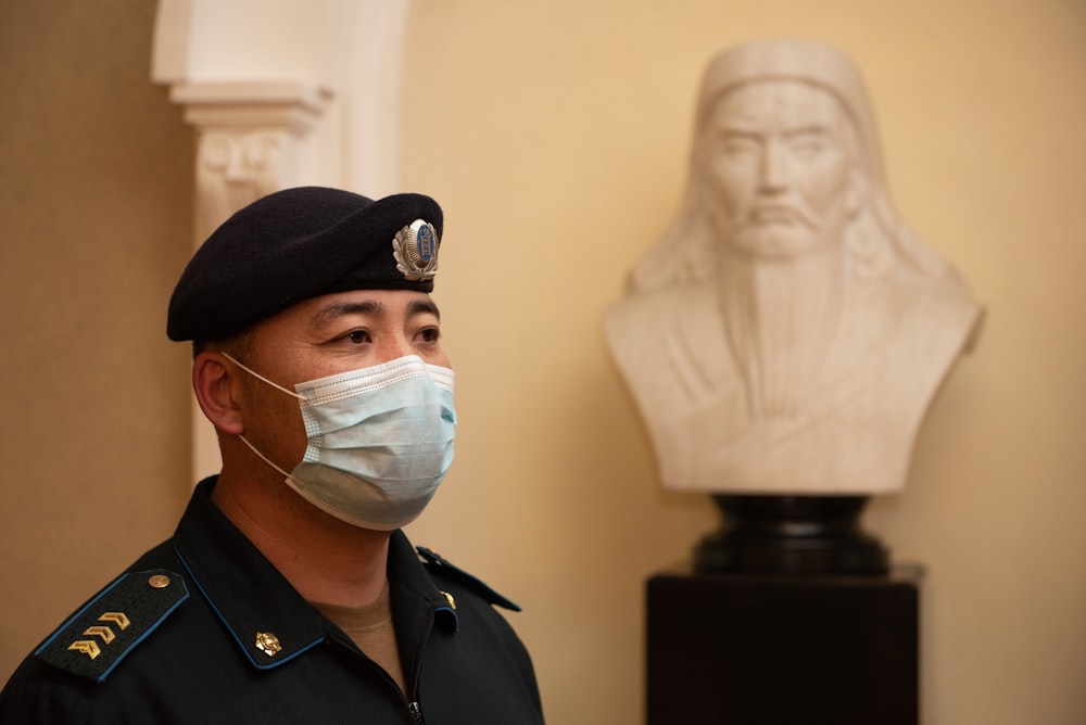 Un hombre con una máscara facial junto a un busto de un hombre