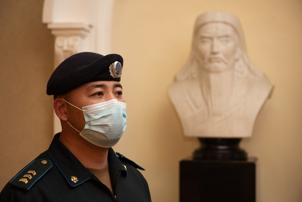 a man wearing a face mask next to a bust of a man