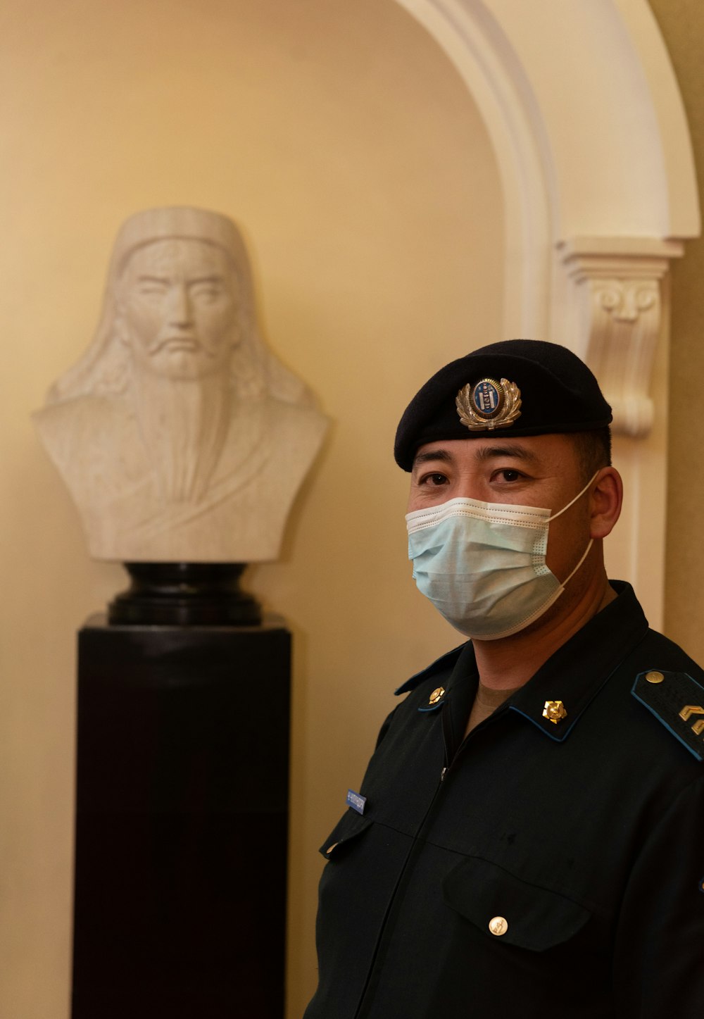 a man wearing a face mask in front of a bust of a man