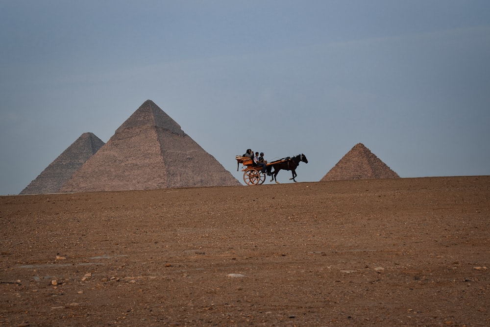 a horse drawn carriage in front of three pyramids