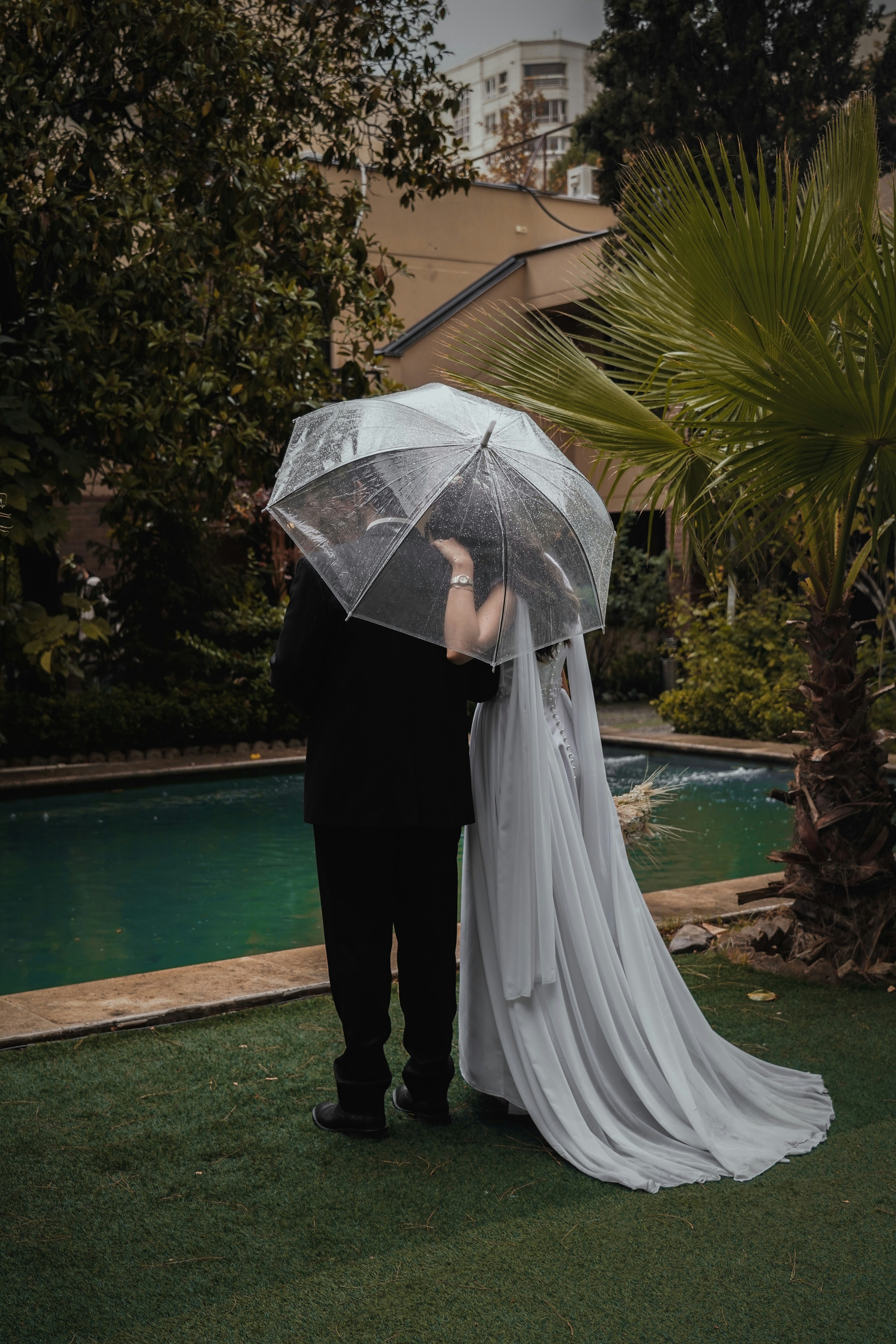 a bride and groom standing under an umbrella