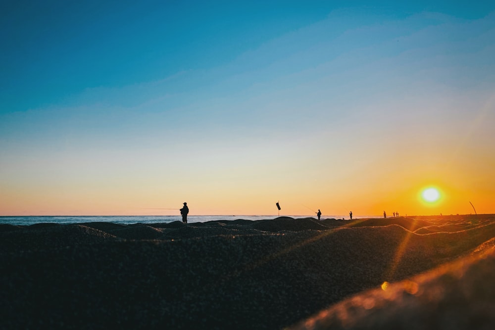 a group of people standing on top of a sandy beach