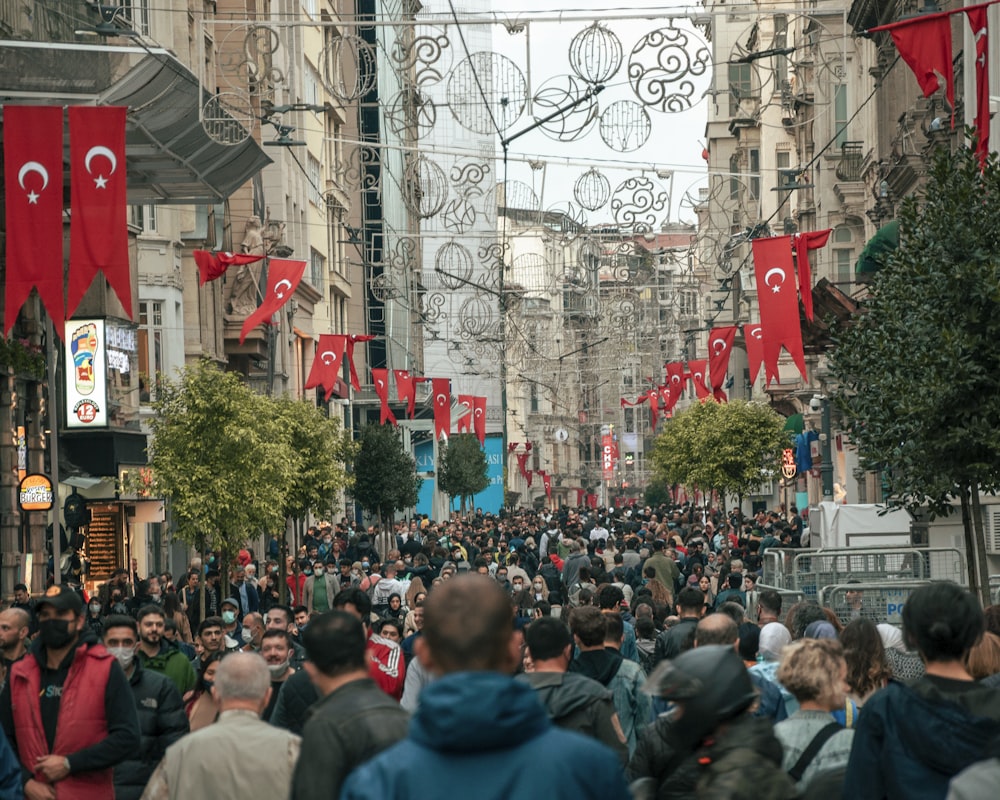 a crowd of people walking down a street next to tall buildings