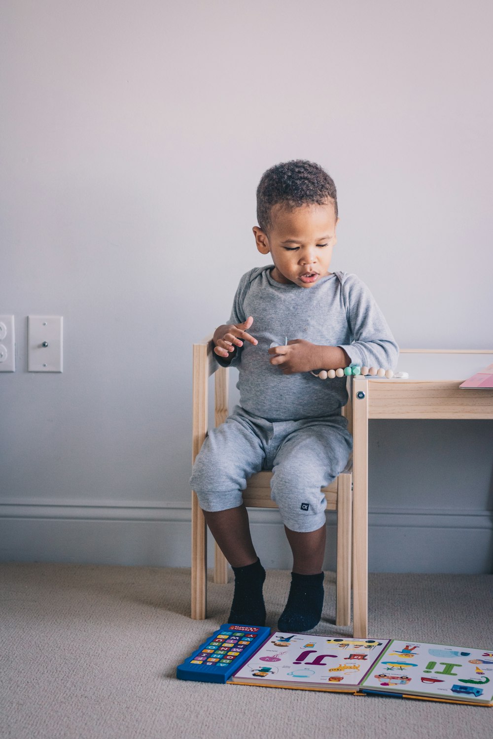 a little boy sitting on a chair playing with his toys