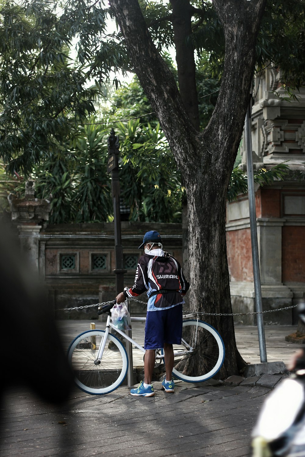 a man standing next to a bike under a tree