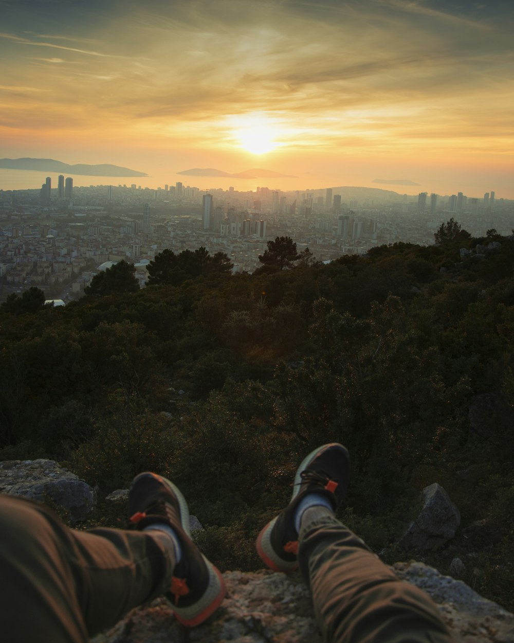 a pair of feet resting on a rock overlooking a city