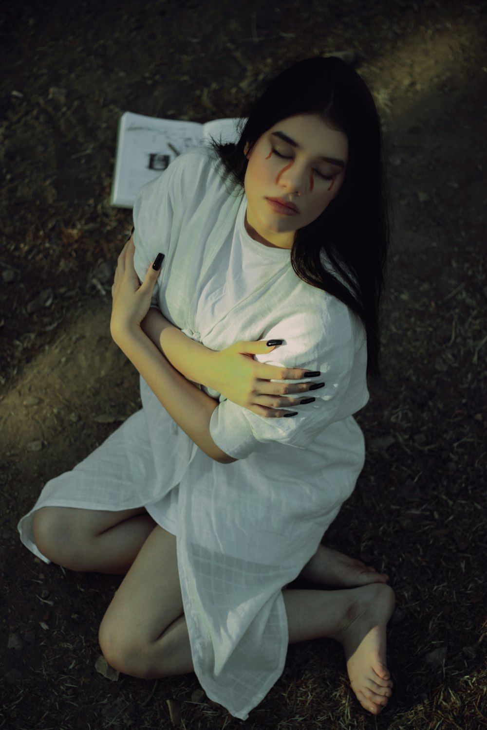 a woman in a white dress sitting on the ground