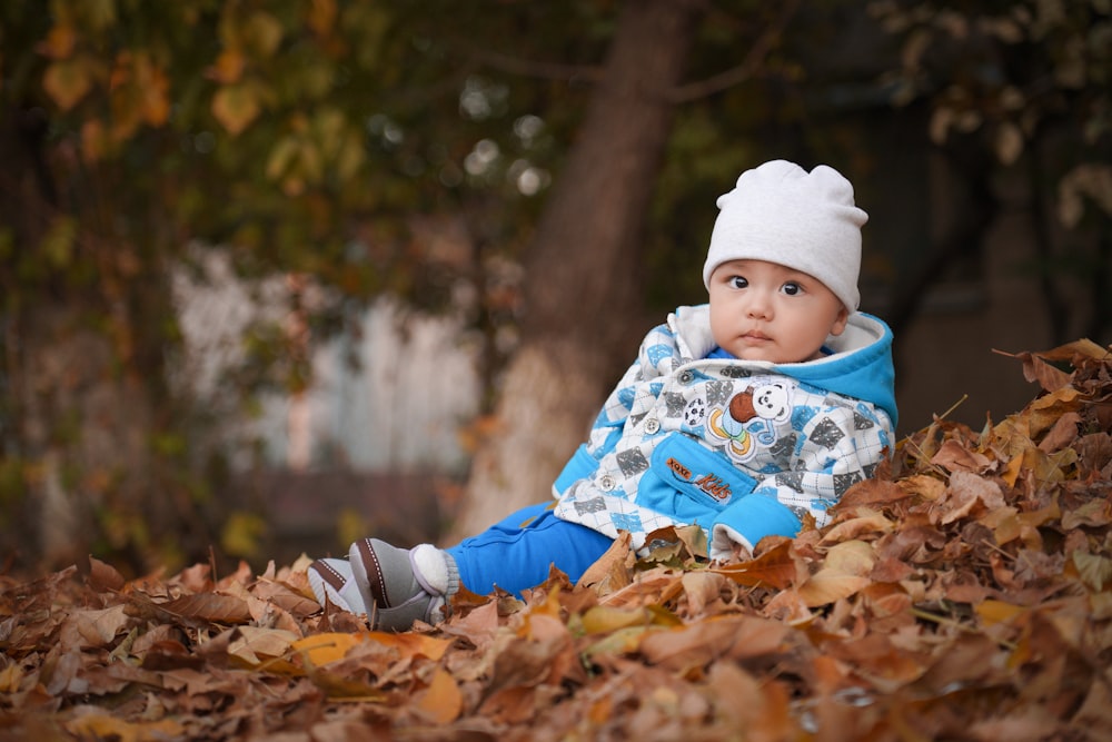 a baby is sitting in a pile of leaves