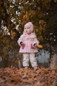 a little girl standing in a pile of leaves