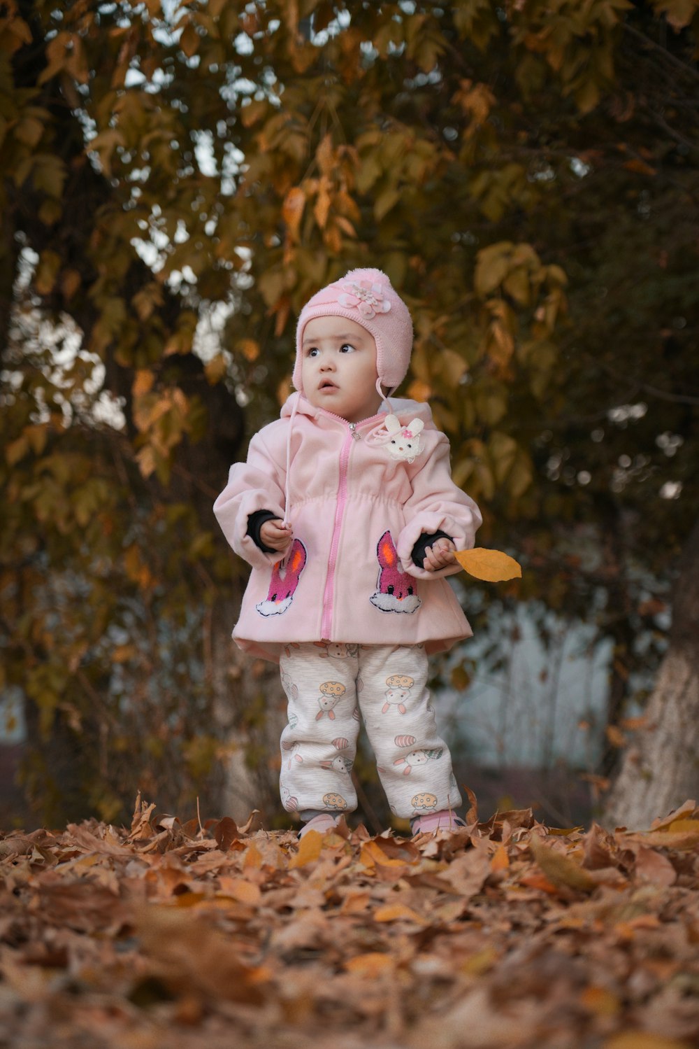 a little girl standing in a pile of leaves