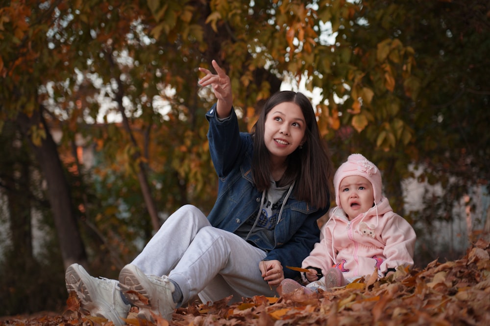 a woman and a baby sitting in leaves