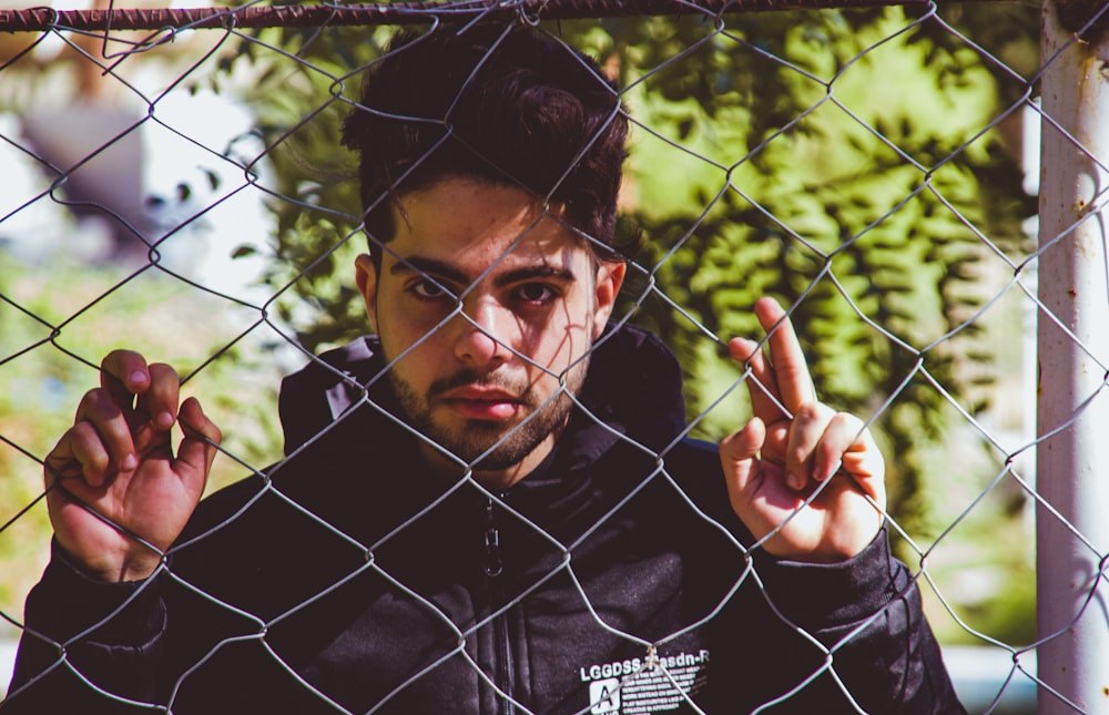 a man standing behind a chain link fence