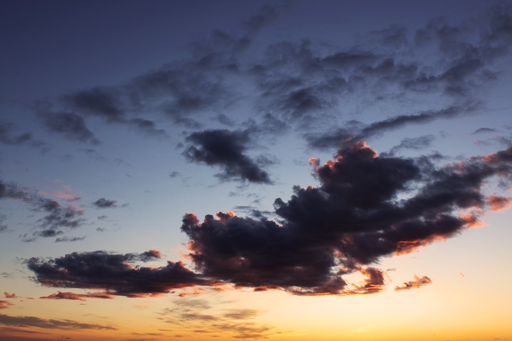 a plane flying in the sky at sunset