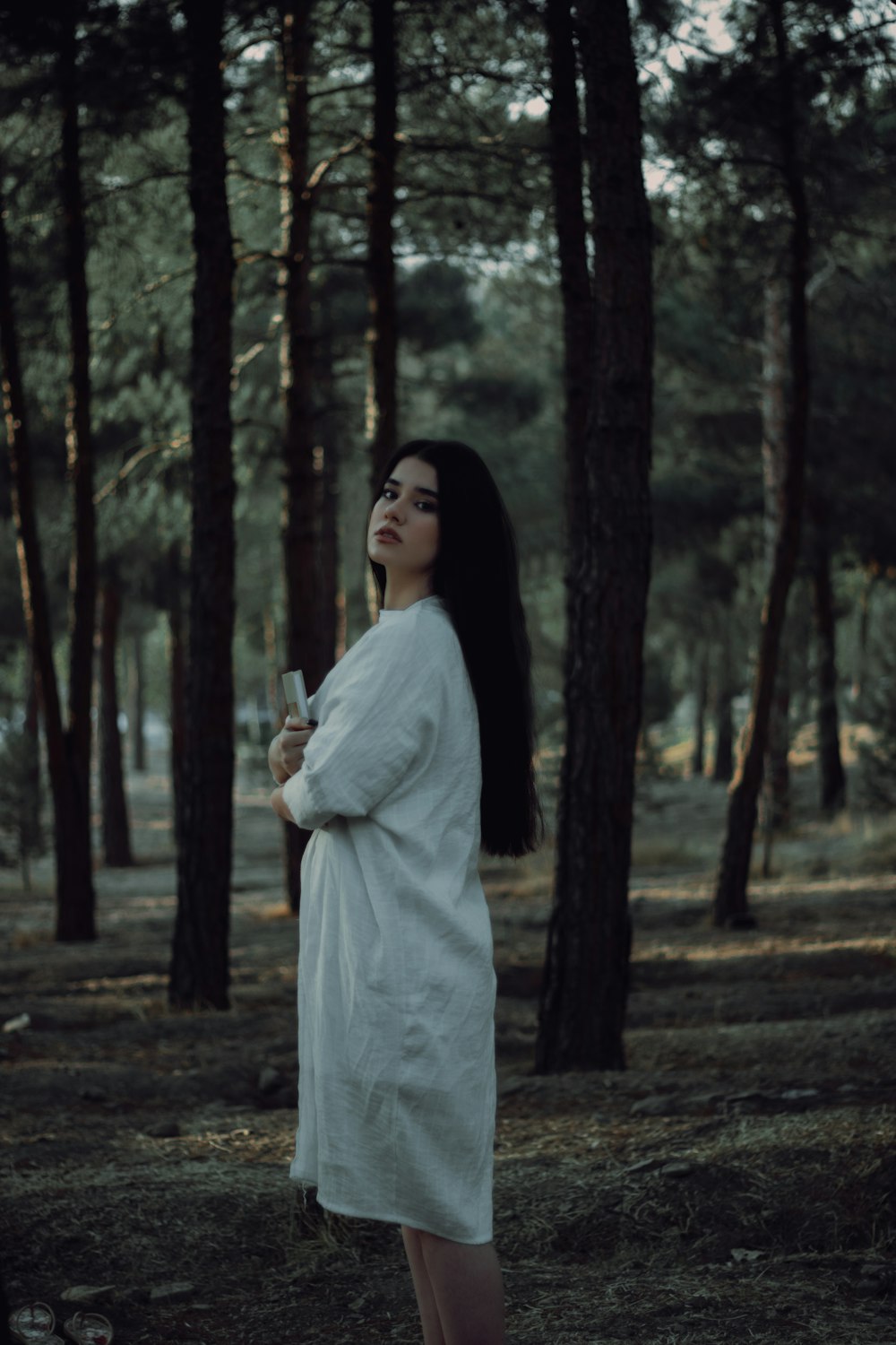 a woman in a white robe standing in a forest